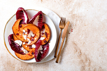 Roasted pumpkin salad with radicchio leaves, feta cheese, nuts and cranberries. Thanksgiving side dish dinner recipe. Healthy seasonal fall or autumn food