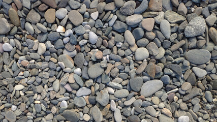 Round stones and pebbles on the beach as background, texture