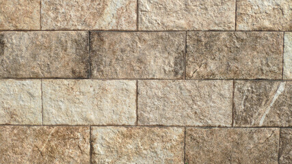 A stone wall as a background or texture. Example of masonry as exterior wall cladding. Rectangular bricks.