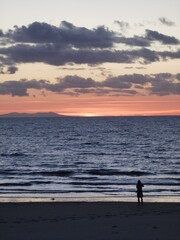 Fototapeta na wymiar Sunset, beach, sea, sand, clouds. Person silhouette