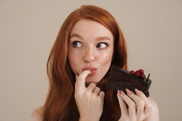 Photo of pleased redhead shirtless girl eating chocolate cake