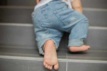 little baby feet, baby crawling stairs, attention and safety with a one-year-old baby