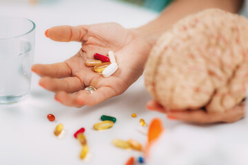 Cognitive improvement or brain supplements. Woman holding a supplement capsule and a model brain.