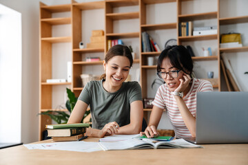 Image of nice multinational student girls doing homework with laptop