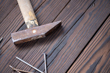 Old vintage hammer and nails on a wooden background, close-up, selective focus.