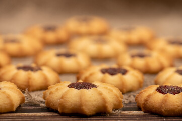 Homemade pastry cookies with jam on a background of homespun fabric with a rough texture, close-up, selective focus.