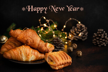 Christmas or New Year pastries, Chocolate and Apple Croissants. Christmas Eve mood. Winter holidays concept with text - Happy New Year. Dark background