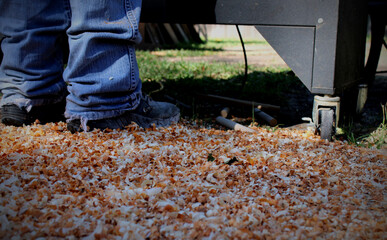 Wood shavings scattered on ground as man works lathe.