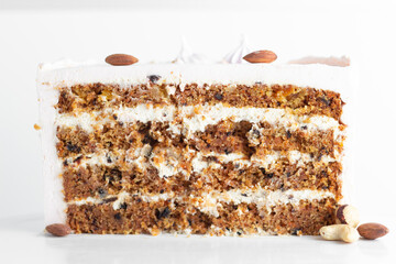Carrot cake slice with almond nuts on the white stand. Cake cut on white background.