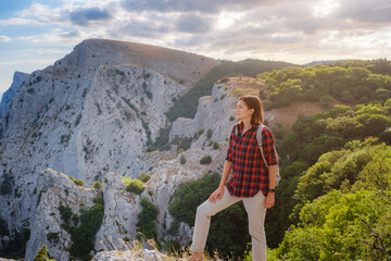 Naklejka premium Fit female hiker with backpack standing on a rocky mountain ridge