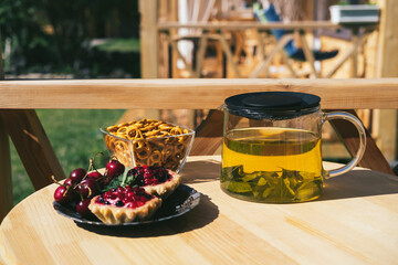 cookies, baskets with lingonberries, pies, strawberries, fruit jelly, cakes and tea from natural herbs on wooden desk. Sunny Breakfast outdoors