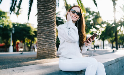 Fototapeta premium Smiling woman talking on phone through earphones
