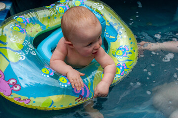 Being watched by both mom and grandma a baby child is playing in hot tub with a floating boat...