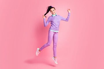 Fototapeta na wymiar Full length photo of cheerful girl jump hold her pigtail wear purple clothes isolated on pastel pink color background
