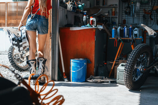 Female wearing shorts, motorcycle boots standing in garage