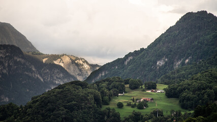 Fototapeta na wymiar Distant steading in green alpine mountains. 