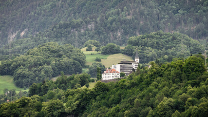 Fototapeta na wymiar Houses on green slope of alpine hills.