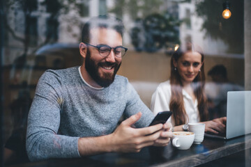 Fototapeta premium Man messaging on phone meeting with female in cafe
