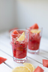 Fresh watermelon refreshing summer cocktail smoothie with lemon and ice in glass mug on white wooden board