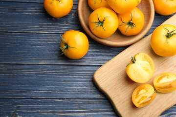 Ripe yellow tomatoes on blue wooden table, flat lay. Space for text