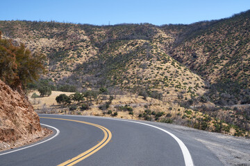 A curvy empty road among burnt hills in California