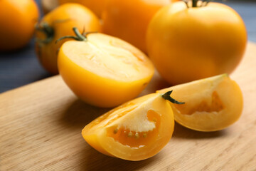Ripe yellow tomatoes on wooden board, closeup