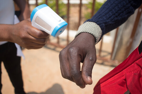 Thermometer being used to detect signs of coronavirus by measuring the hand temperature 