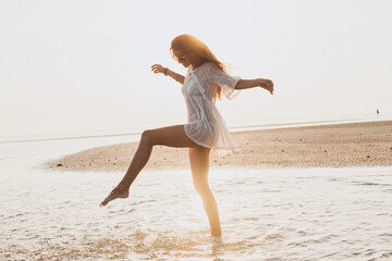 young slim beautiful woman on sunset beach, playful, dancing, running, bohemian outfit, indie...