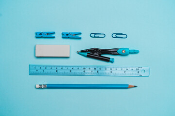 book, pencil, ruler on a blue background.