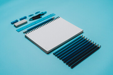 book, pencil, ruler on a blue background.