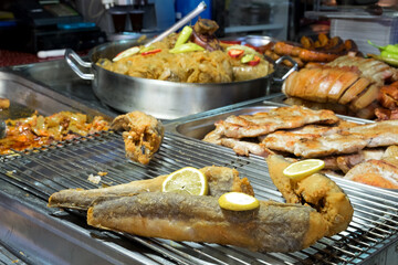 The fresh and healthy Hungarian and Balkan fast food on the holiday street market - delicious roasted fish, grilled sausage, meat steak and chicken skewer with vegetables