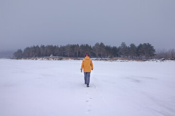 A young man walks alone on a frozen river