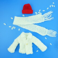 Red hat, knitted scarf  on a blue background. Winter clothes concept. Top view, flat lay.