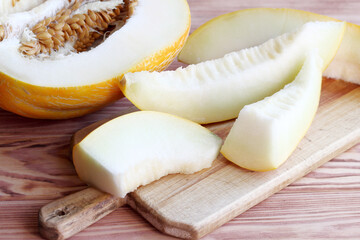 Half melon and sliced pieces of fruit on a wooden board