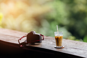 Camera and coffee on wood table in coffee shop.