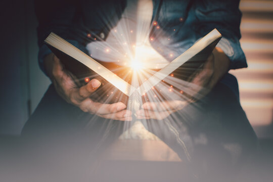The light coming from the book in the hand of man concept wisdom religion reading imagination.