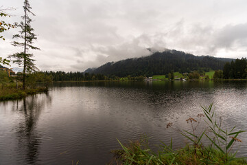 Fototapeta na wymiar Rundweg am Schwarzsee bei Kitzbühel in Tirol bei Regen und Wolken