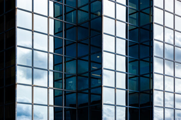 Contemporary blue glass and metal facades of skyscrapers full of offices. Cornered exterior design playing with light and shadow.