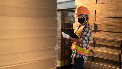 Factory worker wearing face mask and eye protective inspecting product at Wearhouse or workplace.