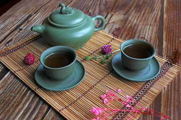 Traditional tea ceremony arrangement. Iron teapot, cups, dried rose buds over wooden table background