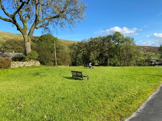 Halton Gill green, with wooden benches and a large old tree, in the heart of, Littondale, Skipton, UK
