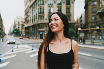 Young beautiful caucasian model look woman wearing trendy clothes posing to the camera while standing on a city road background. Stylish Tourist girl enjoying walking the city during weekend trip.