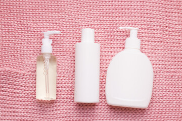 Mockup of cosmetics in a white bottle on the texture of a knitted, warm, pink scarf