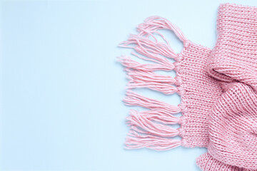 Pink warm knitted scarf on a blue background. Copy space. View from above. Banner