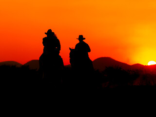 Fototapeta na wymiar The Western Cowboy forced his horses to stop while the sun was setting, In lands where the law has not yet reached