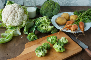 Ingredients for making broccoli soup. On the table are carrots, cauliflower and potatoes.