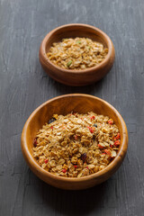On a black background in wooden plates are muesli from sprouted grains of wheat, barley and rye, with the addition of cranberries and strawberries