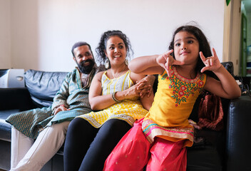 Indian family sitting on couch and enjoy time together - Parents and little child