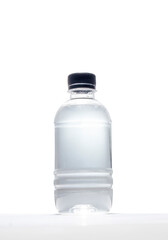 Black screw cap plastic water bottle set on a whBlack screw cap plastic water bottle on white backgroundite table and a white background