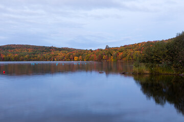 The Delage lake seen at dawn during the Fall season, with colourful wooded mountains in the background, Lac-Delage, Quebec, Canada